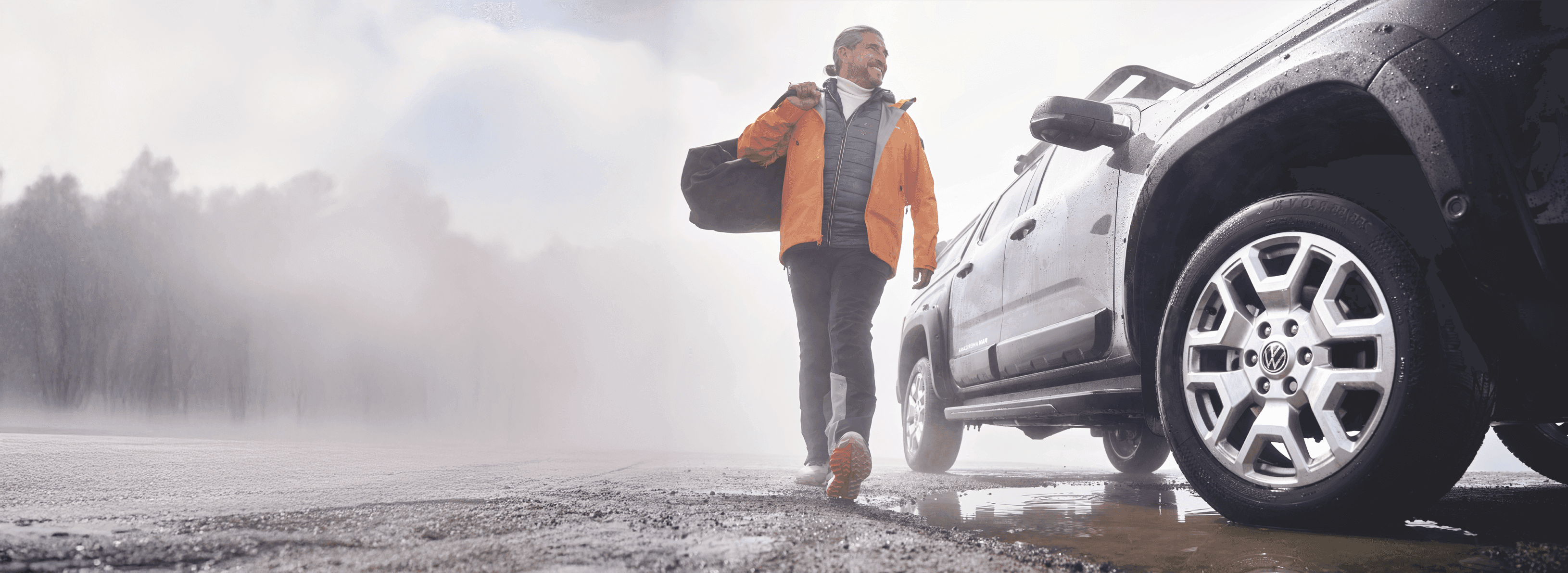 Mężczyzna na tle samochodu w zimowym krajobrazie.